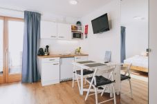 Dining room in Haus Altenberger Apartments by we rent, with a table, chairs, and a kitchen with a stove, oven.