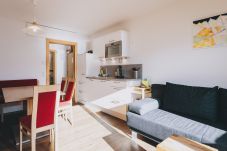 Living area in Apartments Haus Altenberger by we rent. Sofa bed, dining table, and kitchen with stove and oven.