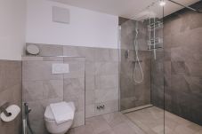 Badezimmer in Haus Altenberger Apartments by we rent. Moderne Dusche mit Doppelwaschbecken, WC, Handtuch. 