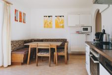 Wohnbereich in der Ferienwohnung Apartments Haus Altenberger by we rent. Esstisch, Küche mit Herd, Ofen.